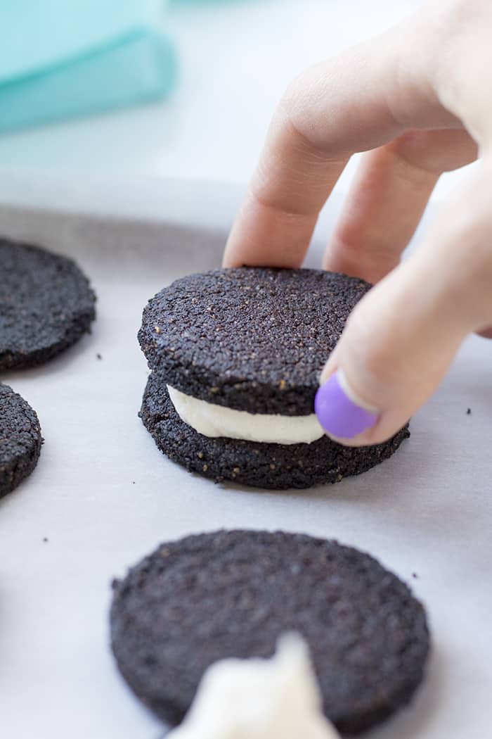 making keto oreos, hand placing cookie on top