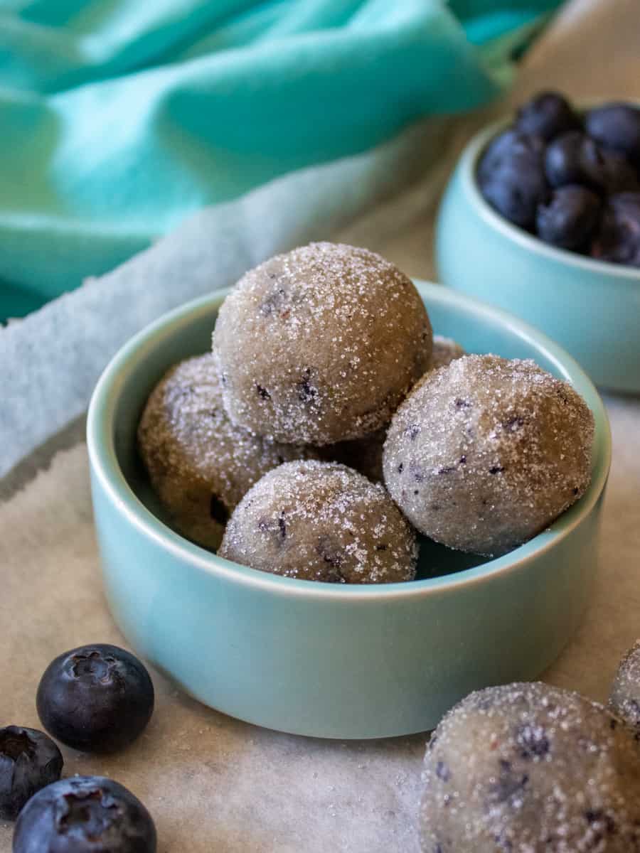 Bowl of Low-Carb Blueberry Donut Holes with blueberries and donut holess in the foreground