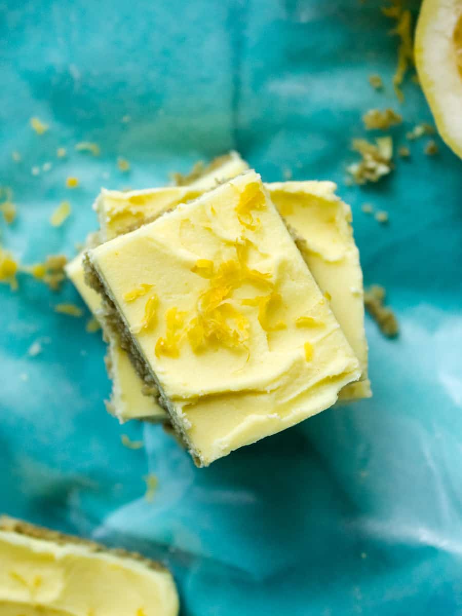 overhead view of yellow cheesecake bars stacked high, lemon zest garnish