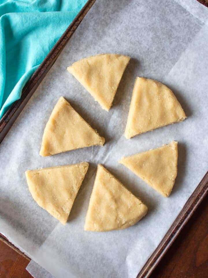 triangular raw dough shapes on parchment lined pan