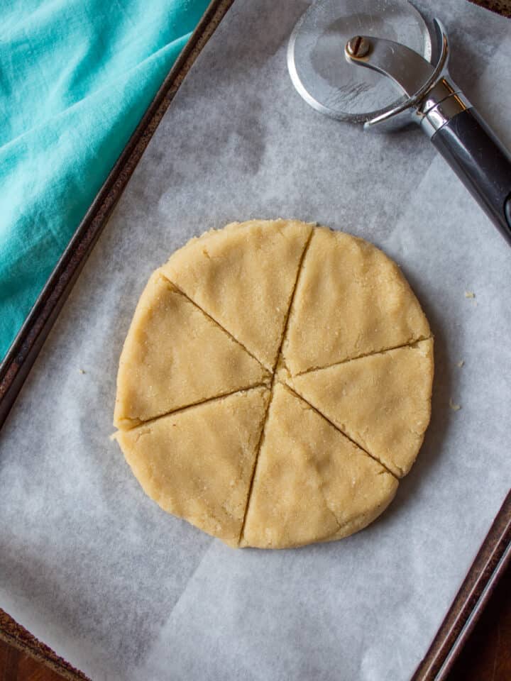 disc of dough with triangular cuts on parchment lined pan