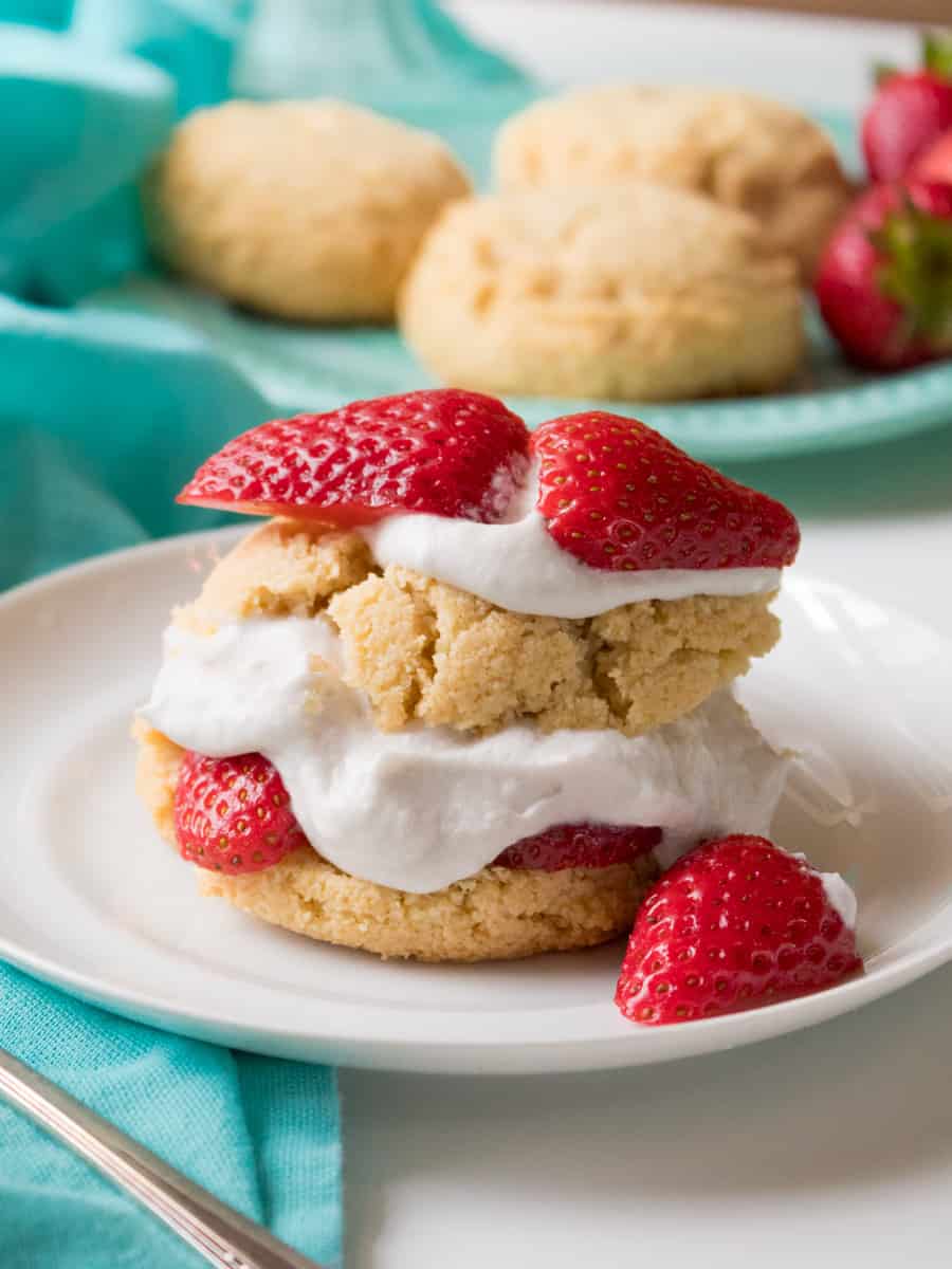 plate shortcakes layered with whipped cream and strawberries, more cakes in the background