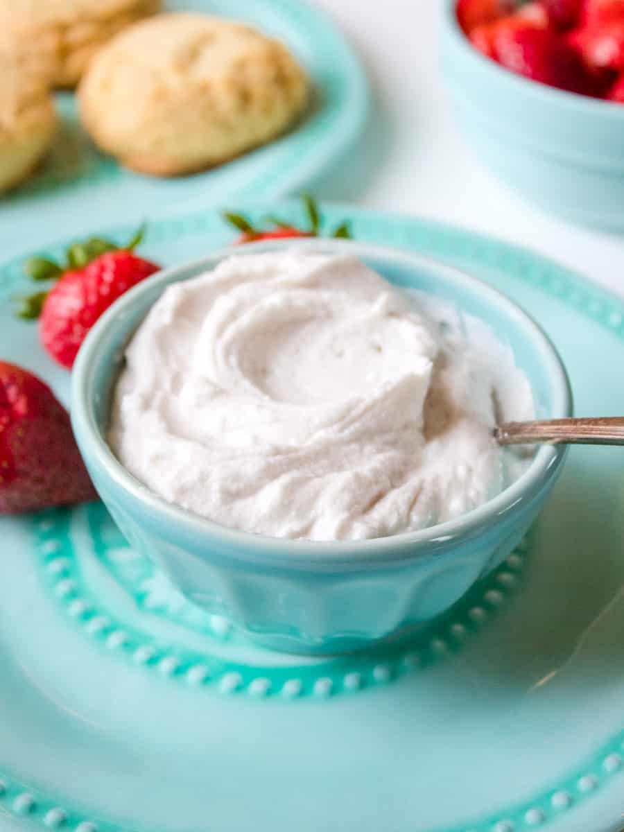 bowl of whipped cream with strawberries in the background